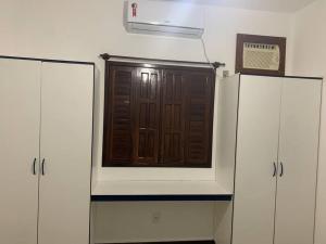 - une porte en bois dans une pièce avec des armoires blanches dans l'établissement Bangalô 6 praia de Guaratiba prado BA, à Prado