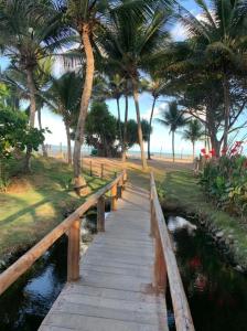 un pont en bois sur une rivière avec des palmiers dans l'établissement Bangalô 6 praia de Guaratiba prado BA, à Prado