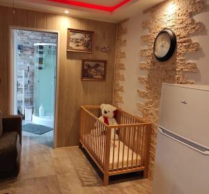 a teddy bear in a crib in a room with a refrigerator at Logement entier agréable et accueillant in Vaulx-en-Velin