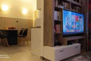 a living room with a tv and a white entertainment center at Logement entier agréable et accueillant in Vaulx-en-Velin