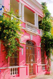 Uma casa cor-de-rosa com um portão à frente. em Casa Rosa - Alma Hotels em Santa Marta