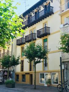 budynek z balkonami i drzewem przed nim w obiekcie Casa La Marina w mieście Hondarribia