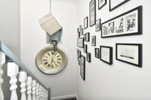 a staircase with a clock and pictures on the wall at Townhouse @ Aboyne Close Birmingham in Birmingham