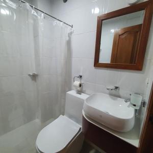 a bathroom with a toilet and a sink and a mirror at Hotel Bonanza in Guayaquil