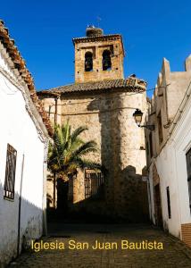 un edificio antiguo con una torre de reloj con una palmera en AGUA DULCE , Apartamento Rural, en Herrera del Duque