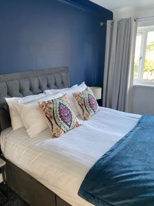 a bed with two pillows and a blue wall at Stylish 3 bed house, private parking, garden and conservatory in Sheffield