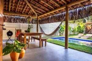 a patio with a table and a hammock and a pool at Casa Jenipapo Trancoso - Sinta o pedacinho do céu in Trancoso