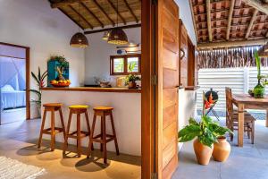 a kitchen with a bar with stools and a table at Casa Jenipapo Trancoso - Sinta o pedacinho do céu in Trancoso