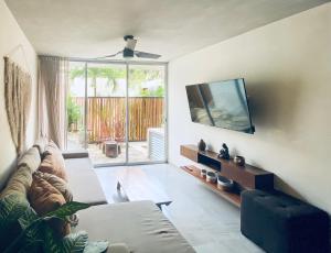 a living room with a couch and a flat screen tv at Casa Azul 2 BedBath in Tulum