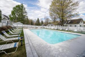 a large swimming pool with lawn chairs and a house at All Season Mountain Retreat in Dover