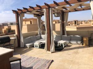 un patio con sofás y un cenador en la azotea en Modern Pool View Appartment with Rooftop Extension en Sharm El Sheikh