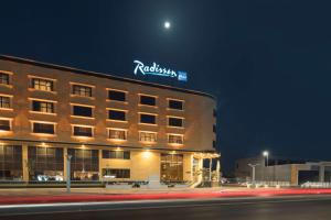a hotel with a sign on top of it at night at Radisson Blu Hotel, Buraidah in Buraydah