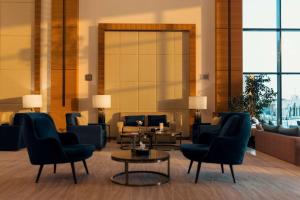 a lobby with blue chairs and tables and windows at Radisson Blu Hotel, Buraidah in Buraydah +113 photos