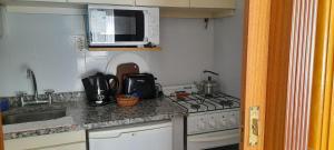 a small kitchen with a stove and a microwave at Legarra 1 in Miramar +5 photos