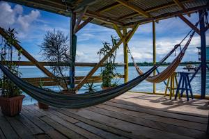 eine Hängematte auf einer Terrasse neben dem Wasser in der Unterkunft Hostal On The Sea in Bocas del Toro