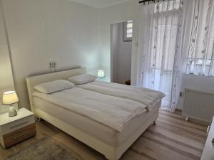 a white bedroom with a large bed and a window at Apartman Lana in Bosanski Novi