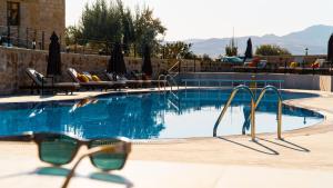 une paire de lunettes de soleil assise à côté d'une piscine dans l'établissement MDC Cave Hotel Cappadocia, à Ürgüp