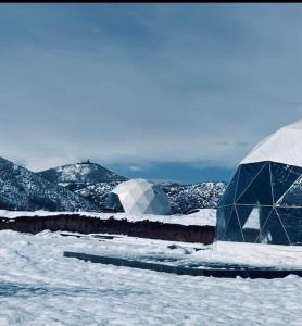 duas cúpulas na neve com montanhas ao fundo em Bolnisio Resort em Bolnisi