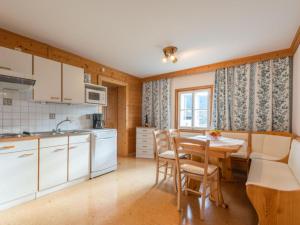 フラッハウにあるSiglavy Flachauの白いキャビネット、テーブルと椅子付きのキッチンが備わります。