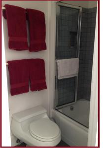 a bathroom with a toilet and a shower and red towels at Beautiful Edwardian Victorian Homestay B&B in San Francisco