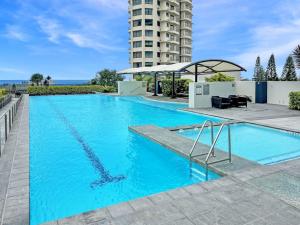 a large blue swimming pool with a tall building in the background at Sub Penthouse Oracle 46th floor - GC Getaways in Gold Coast