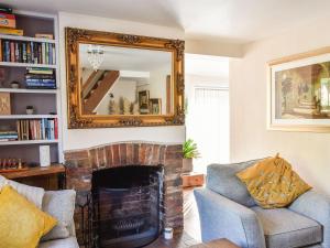 a living room with a fireplace and a mirror at Arun Cottage in Loxwood