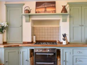 a kitchen with green cabinets and a stove top oven at Arun Cottage in Loxwood