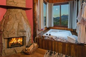 a bathroom with a large stone tub with a fireplace at Pousada Lua de Minas in Visconde De Maua