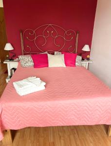 Una cama rosa con dos toallas blancas. en Habitación Hemerocallis - Hospedaje Lo De Juan y Mabel en Tandil