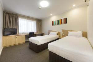 Habitación de hotel con 2 camas y TV de pantalla plana. en Ramada Encore Belconnen, en Canberra