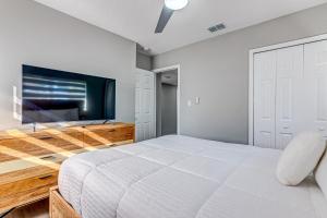Schlafzimmer mit einem weißen Bett und einem Flachbild-TV in der Unterkunft Suwannee Lane in Cocoa Beach