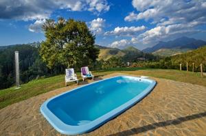 una piscina con 2 sillas de jardín junto a ella en Pousada Lua de Minas, en Visconde De Maua