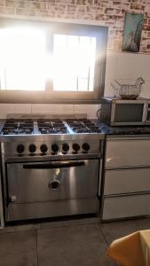 a kitchen with a stove and a microwave at Hospedaje El Ciruelo in Alta Gracia
