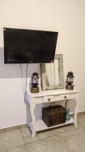 a flat screen tv on a white table with two lights at Hospedaje El Ciruelo in Alta Gracia