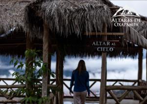 una mujer caminando delante de una cabaña de paja en Altares de Oxapampa, en Oxapampa