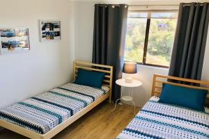 two beds in a room with a window at Promenade 12, 8 Intrepid Cl - fantastic waterfront unit with air con and Wifi in Nelson Bay