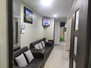 a living room with black leather couches and a tv at Depawanka 1 departamento amoblado in Huancayo