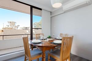 a dining room with a table and chairs and a large window at Bellevue, 7 4 Donald Street - renovated unit with air con and Wi-Fi with views & central to CBD in Nelson Bay