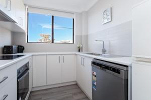 Una cocina blanca con fregadero y lavavajillas. en Bellevue, 7 4 Donald Street - renovated unit with air con and Wi-Fi with views & central to CBD, en Nelson Bay 8 fotos más