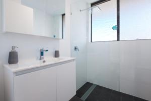 a white bathroom with a sink and a window at Bellevue, 7 4 Donald Street - renovated unit with air con and Wi-Fi with views & central to CBD in Nelson Bay