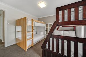 a bedroom with two bunk beds and a ladder at Petersdorf 2 Jindabyne Townhouse in Jindabyne
