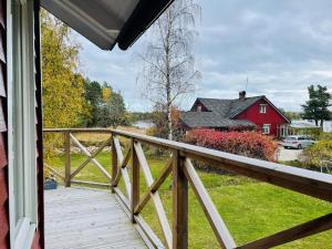 porche con barandilla de madera y granero rojo en Holiday home KÖPMANNEBRO II, en Köpmannebro