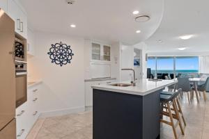 a kitchen with a sink and a counter with chairs at Sirocco 906 in Mooloolaba