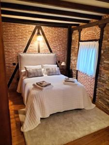 ein Schlafzimmer mit einem weißen Bett mit Ziegelwand in der Unterkunft Casita Merrick in Arenas de San Pedro