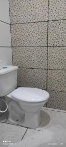 a white toilet in a bathroom with a tiled wall at Hotel Foz Brasil in Foz do Iguaçu