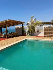 una piscina di fronte a una casa con terrazza in legno di Casa Vistamar y Bungalows a Los Órganos