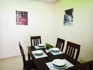 a dining room with a table and chairs and two paintings at NOUVEAU Appartement Totalement neuf - très propre à coté du centre commercial MARJANE in Tangier