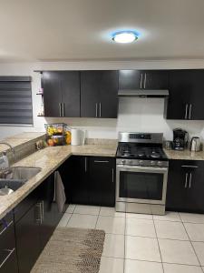 a kitchen with black cabinets and a stove top oven at Casa Luna 2 bedroom Condo 5 min to Border & Beach in Tijuana
