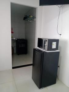 a kitchen with a microwave on top of a refrigerator at KITNET EM OLINDA CASA CAIADA A 50 MT DA PRAIA in Olinda