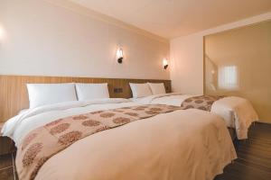 2 Betten in einem Hotelzimmer mit weißer Bettwäsche in der Unterkunft East Town 26 Hotel in Hualien